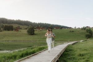 Un couple se courant après sur la passerelle du lac des confins sur la commune de La Clusaz. Ils rient et rayonnent de bonheur.